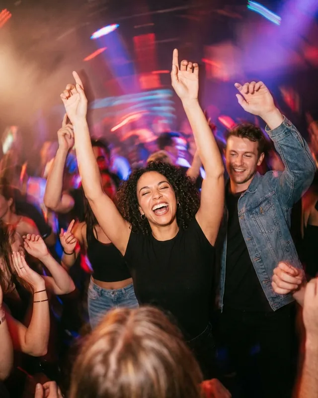 Friends dancing with their arms up on a crowded dance floor